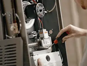Furnace repair technician inspecting internal components and wiring in Milwaukee, WI