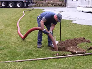 Septic pumping technician servicing a residential septic tank with a vacuum hose in Milwaukee, WI