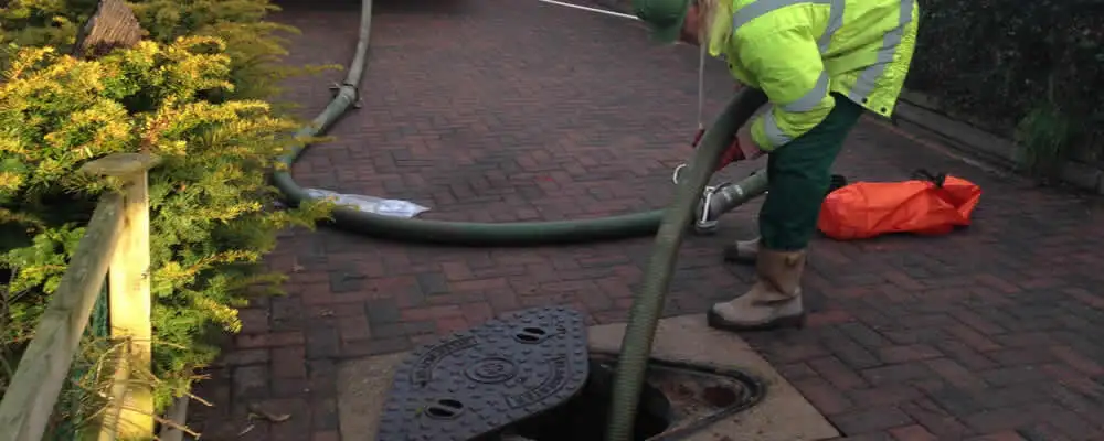 Septic tank cleaning technician servicing a septic tank with a vacuum hose in Milwaukee, WI