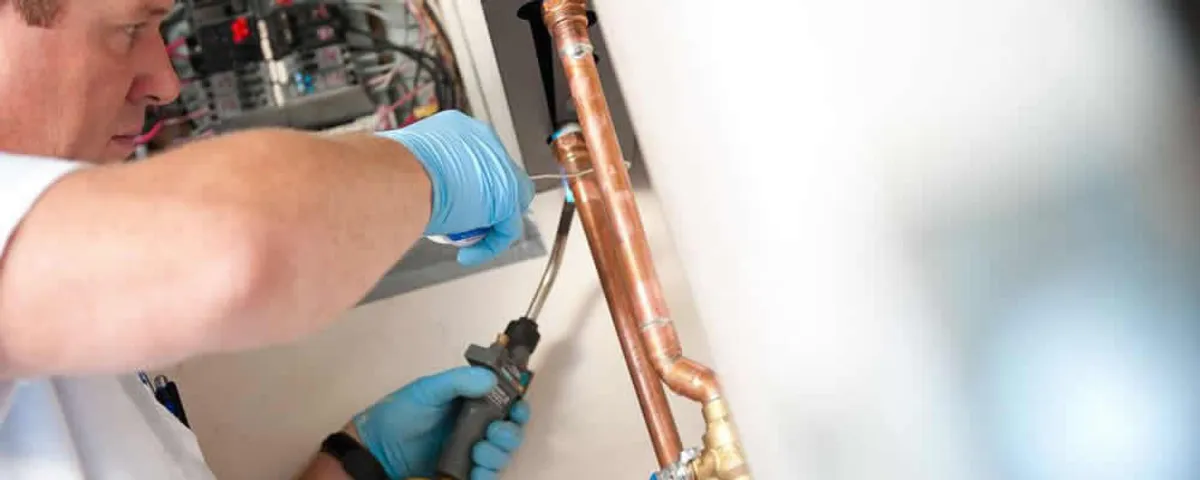 Water heater repair technician testing copper pipe connections and controls in Milwaukee, WI