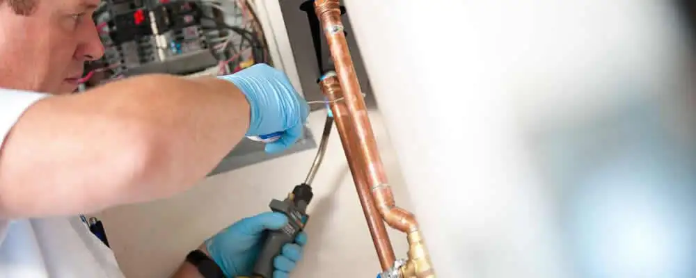 Water heater repair technician testing copper pipe connections and controls in Milwaukee, WI